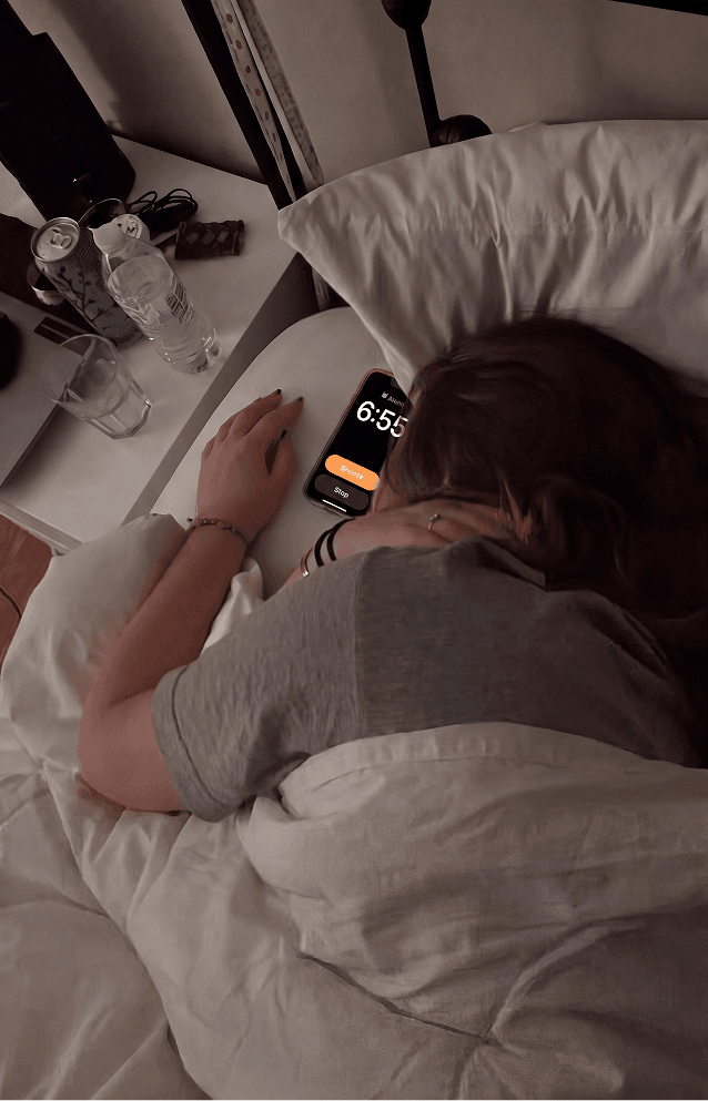 Person snoozing a phone alarm in bed
